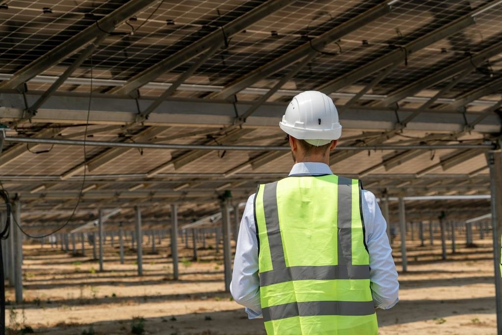 Ingeniero con casco y chaleco bajo una estructura fotovoltaica