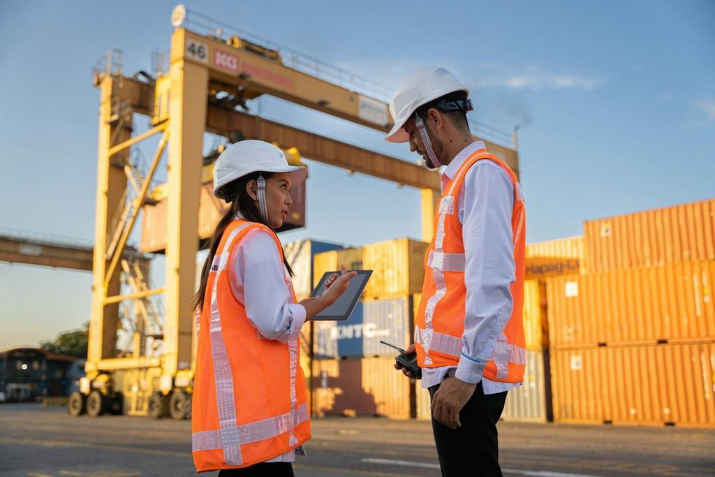 Dos ingenieros con equipo de protección revisan información en una tableta en un entorno industrial